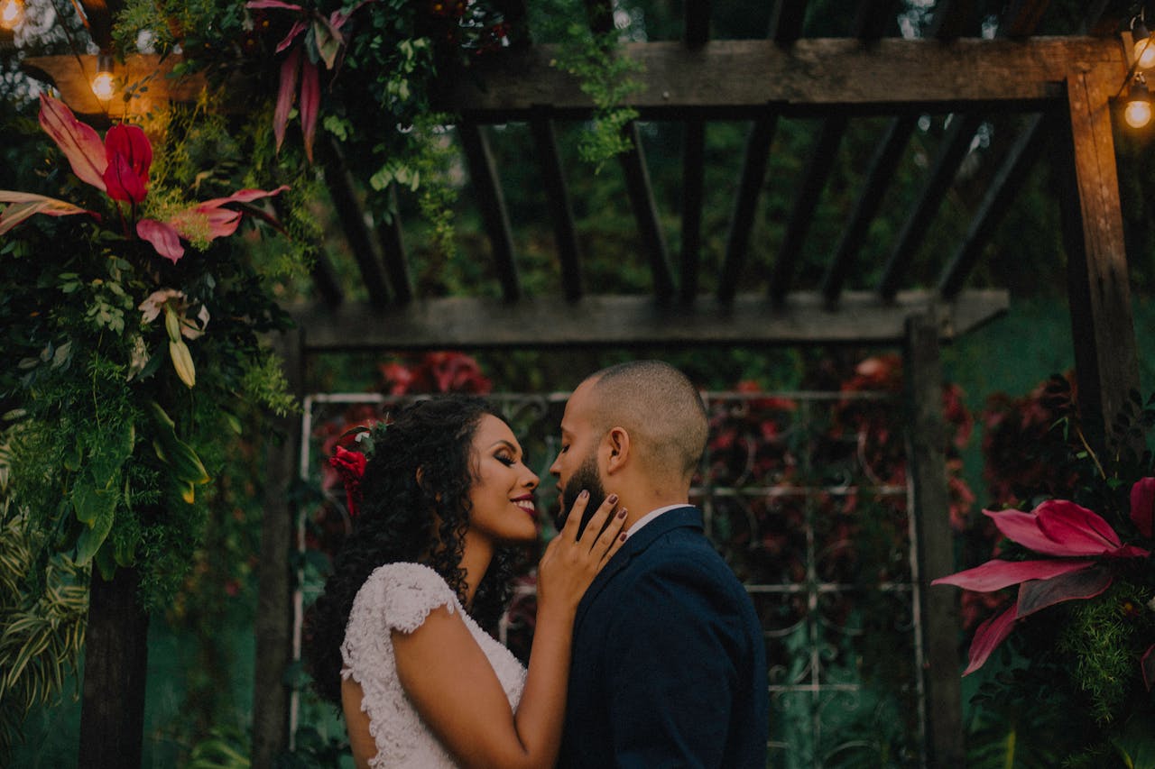 A couple shares an intimate moment during their wedding in a vibrant, lush garden.