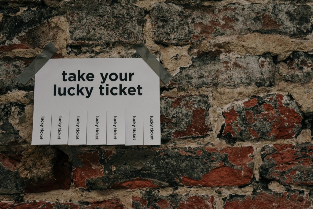 pexels photo 3826577 3826577 Close-up of a 'Take Your Lucky Ticket' sign taped to a rustic brick wall.