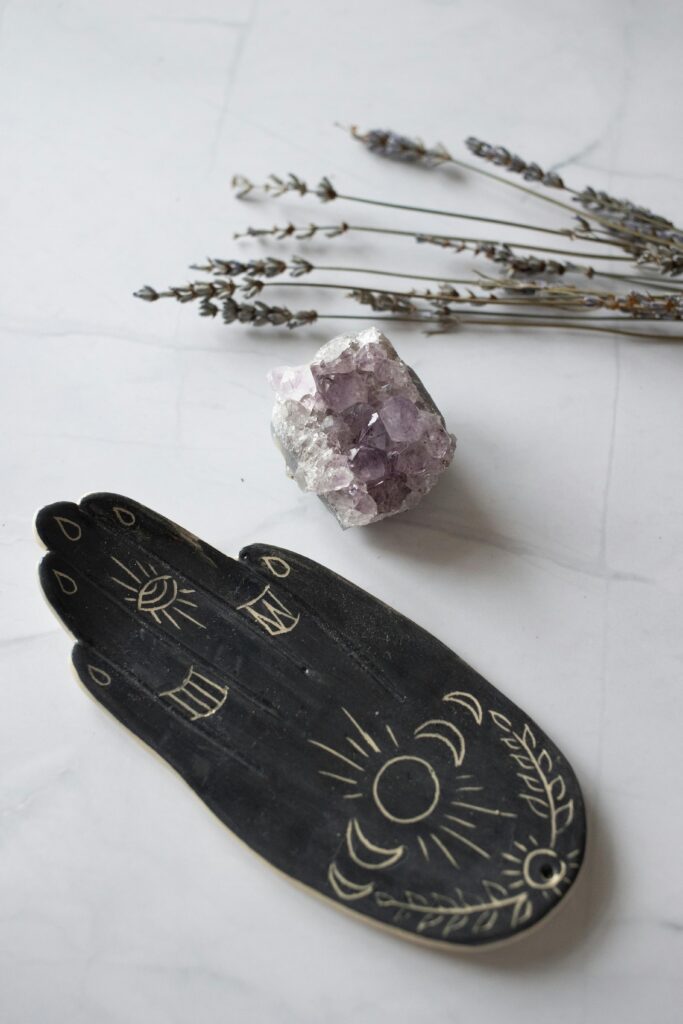 Mystical flat lay featuring an amethyst crystal and esoteric incense holder on a white surface.