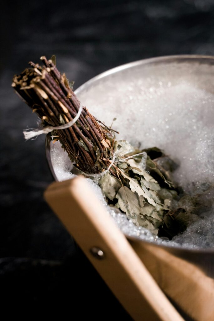 Eucalyptus branches in a rustic bath bucket filled with foam bubbles for relaxation.